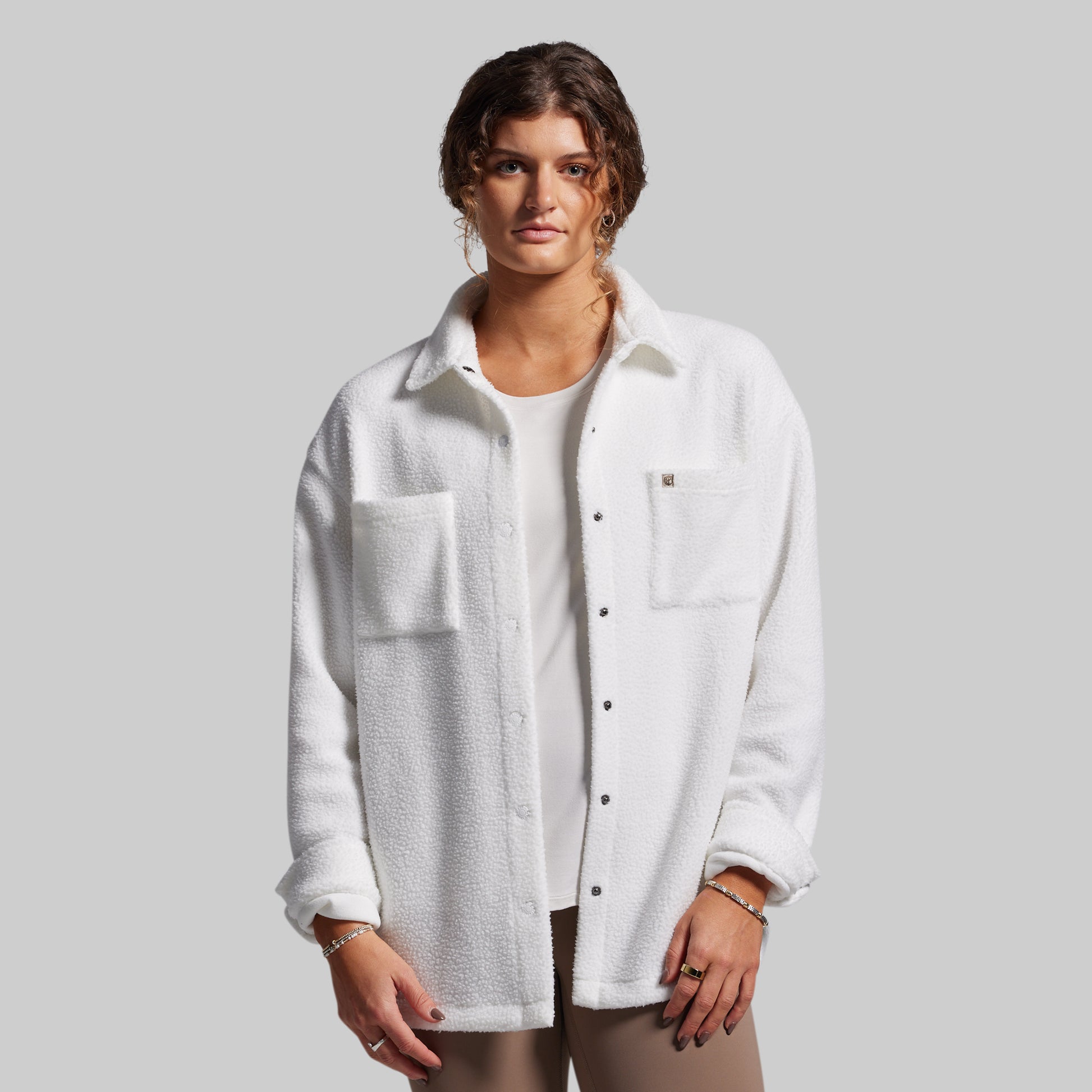 Woman wearing a white textured shirt over a plain shirt on a gray background