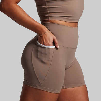 Person wearing brown athletic shorts and top on a light gray background