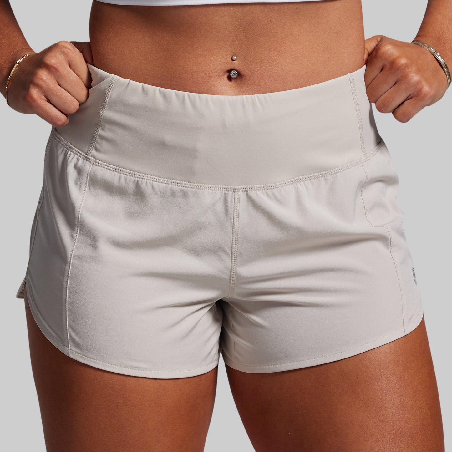 Person wearing light gray athletic shorts on a plain background