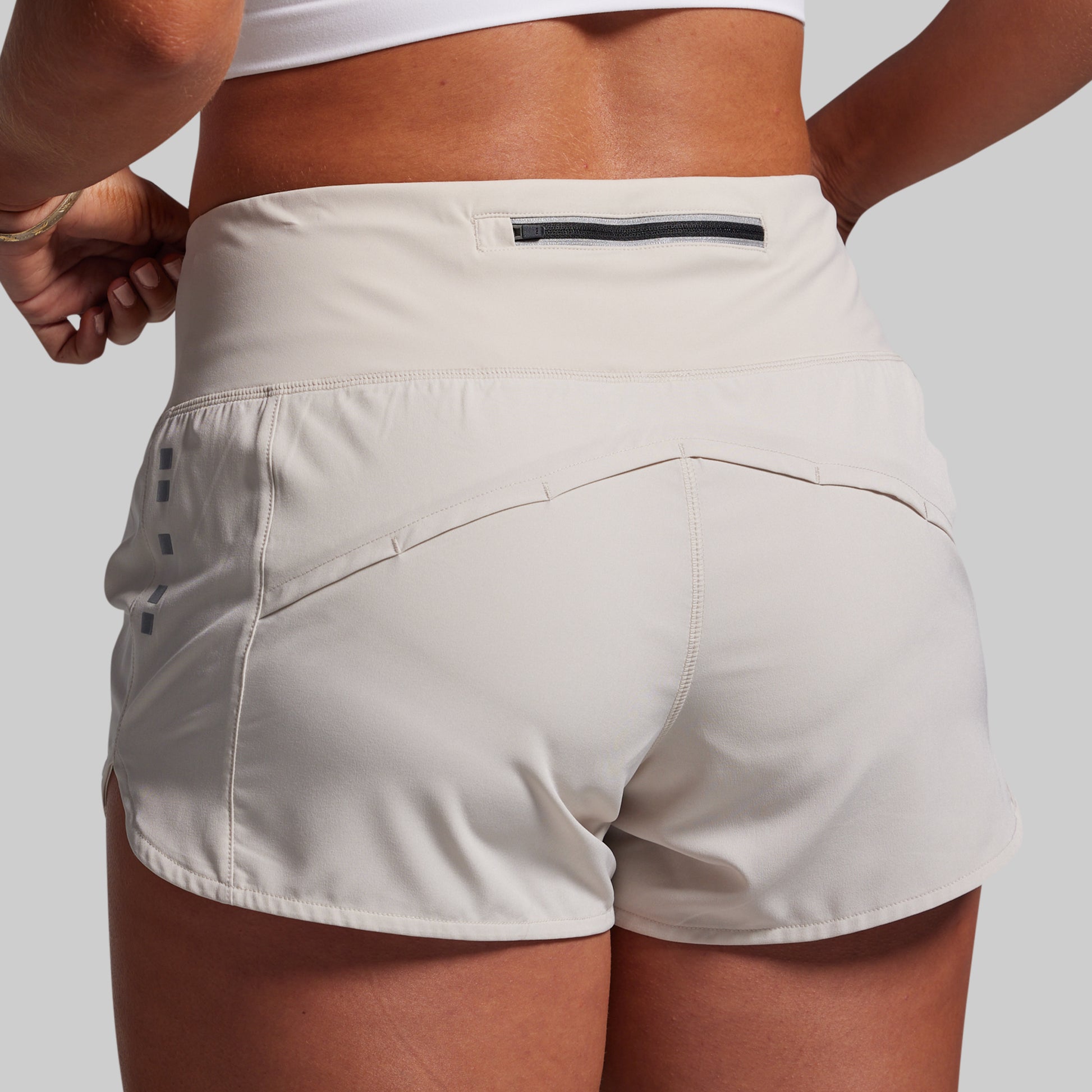 Beige athletic shorts worn by a person on a light gray background