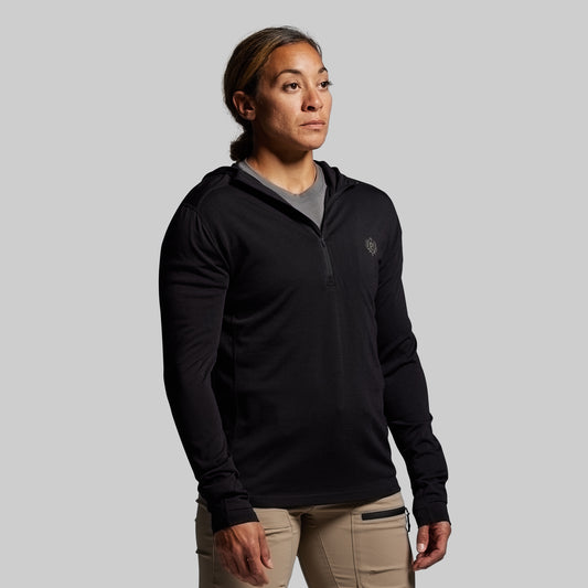 Person wearing a black pullover with a logo on a gray background