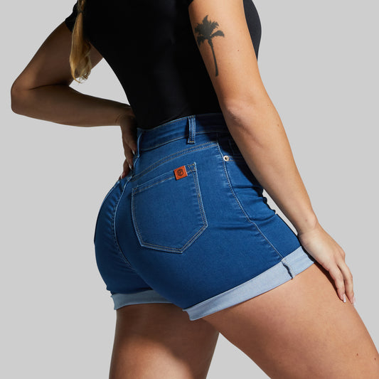 Person wearing blue denim shorts with a brand logo on a gray background