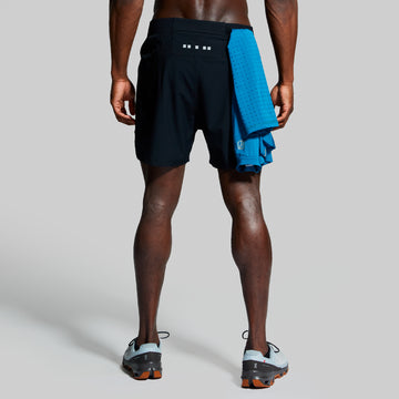 Person wearing black athletic shorts with a blue towel in back pocket on a gray background